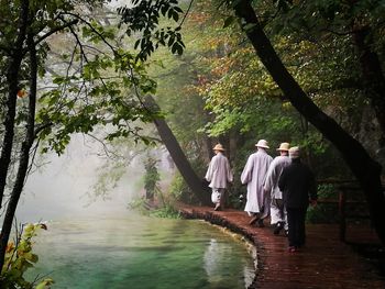 Rear view of men walking in traditional clothing by lake at park