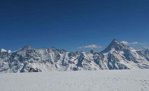 Scenic view of snowcapped mountains against blue sky