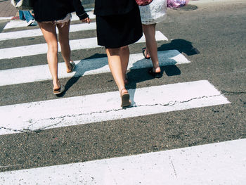 Low section of women walking on road