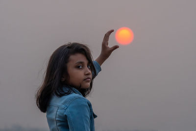 Portrait of young woman playing tennis at sunset