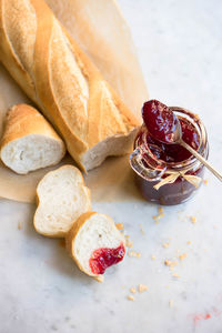 High angle view of baguette and strawberry jam on table