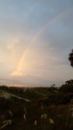 Scenic view of rainbow over field against sky