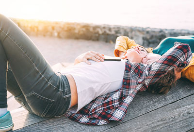 Lesbian couple lying on wood at beach