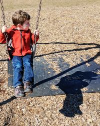 High angle view of boy enjoying on swing at park