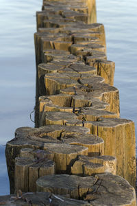Stack of wooden post at beach against sky