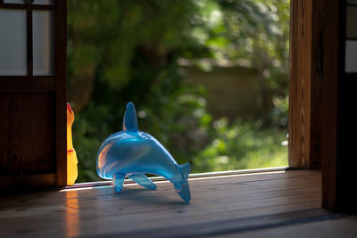Blue toy on window against trees