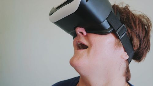 Woman wearing virtual reality simulator against wall