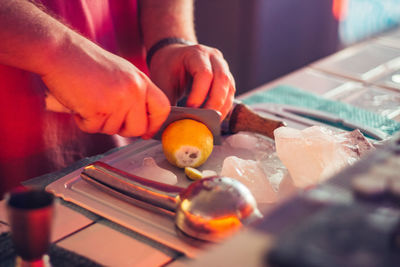 Midsection of man cutting lemon on table