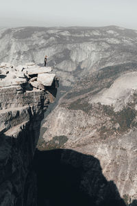 Young woman standing ontop of half dome looking over a cliff