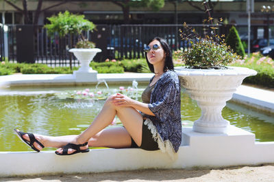 Portrait of young happy brunette asian woman relaxing in city, park. lake. summer vacation. travel