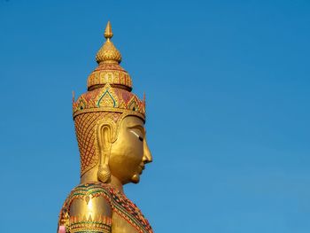 Low angle view of statue against blue sky and building