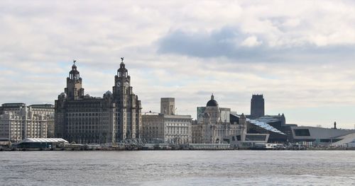 Buildings in city against cloudy sky