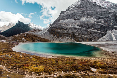 Scenic view of lake by snowcapped mountains against sky