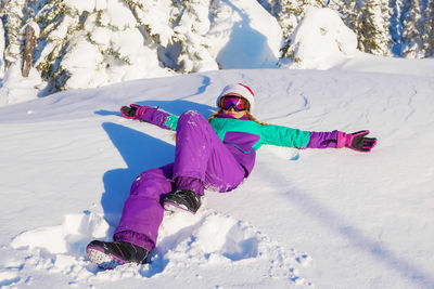 Full length of woman lying down in snow covered land