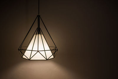 Low angle view of illuminated lamp against wall at night