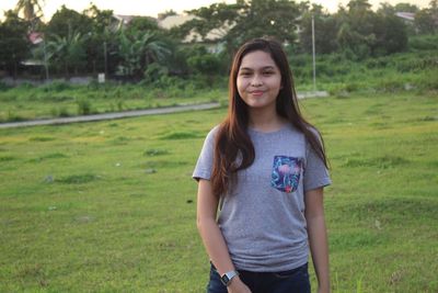 Portrait of smiling young woman standing on grass