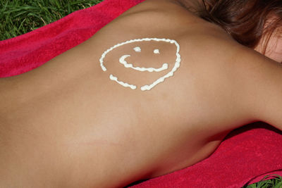Sunscreen smiley face on back of woman lying at back yard