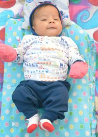 High angle portrait of cute baby boy lying on bed at home