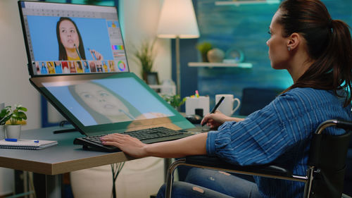 Midsection of woman using mobile phone while sitting on table