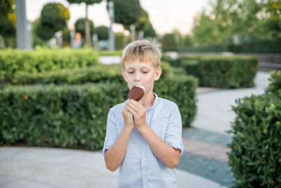 Portrait of boy standing against plants