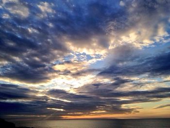 Scenic view of sea against cloudy sky at sunset