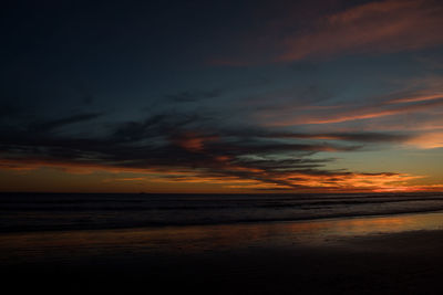 Scenic view of sea against dramatic sky during sunset