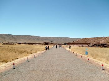 People on desert against clear blue sky