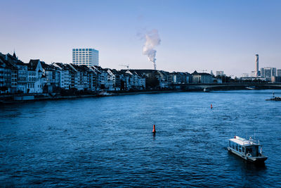 View of factory in basel by river rhine against sky