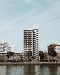 Buildings by river against sky