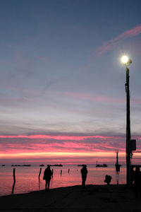 Silhouette people on beach against sky during sunset