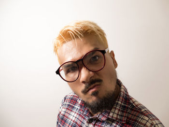 Portrait of young man wearing eyeglasses against white background