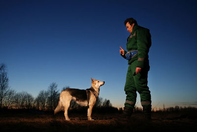 Full length of a dog standing on field against clear sky