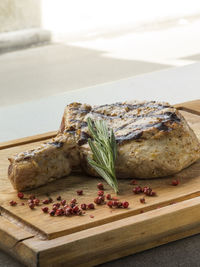 Close-up of fresh grilled beef steak on wooden cutting board with spices