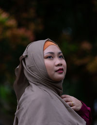 Portrait of young woman looking away outdoors