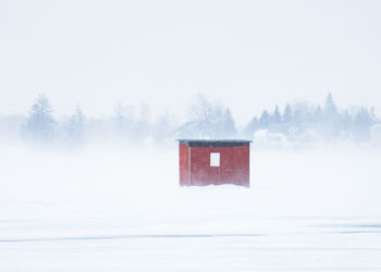 Ice fishing hut isolated in a winter storm surrounded by blowing snow