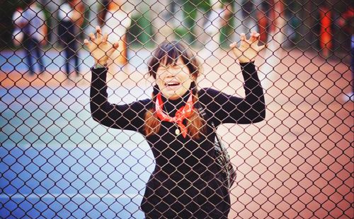 Woman crying while standing by chainlink fence