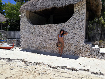 Woman in bikini standing against wall