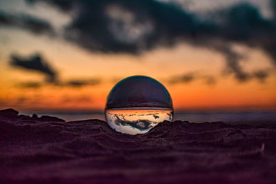 Surface level of beach against sky during sunset