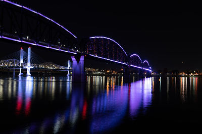 Illuminated bridge over river at night