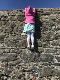 Rear view of woman standing on rock climbing a wall 