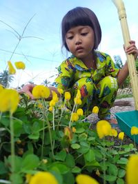 Cute girl on yellow flowering plants on field