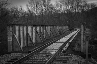 Railroad tracks by bare trees against sky