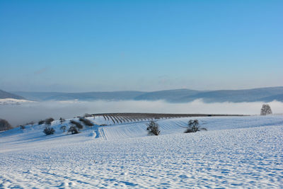 Snow landscape with fields and fog in the valley and with blue sky in spessart, bavaria, germany