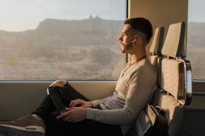 Concentrated male passenger using laptop in train