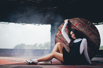 Portrait of young woman leaning on wooden table while sitting on floor