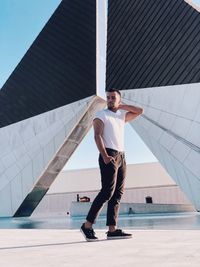 Full length of young man standing against modern building