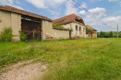 Abandoned house on field against sky