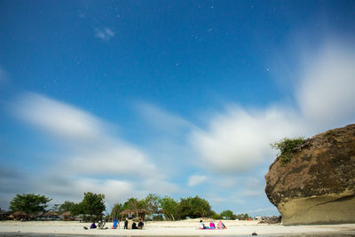 People on shore against blue sky