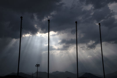 Low angle view of street lights against cloudy sky