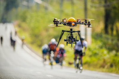 Drone flying over road against people in background